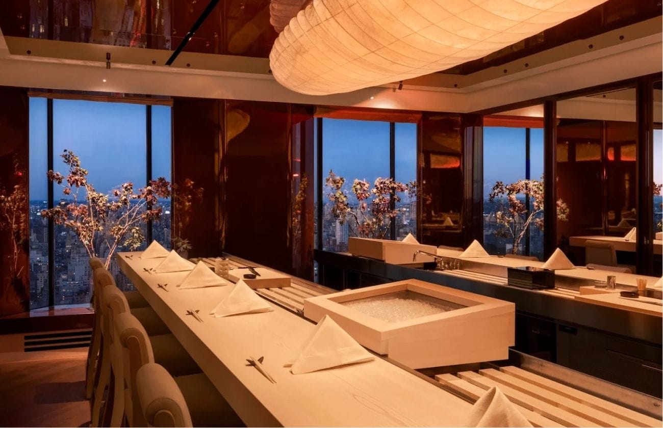 Yūgin’s serene 12-seat omakase counter overlooking the New York skyline, designed with warm hinoki wood and soft ambient lighting.