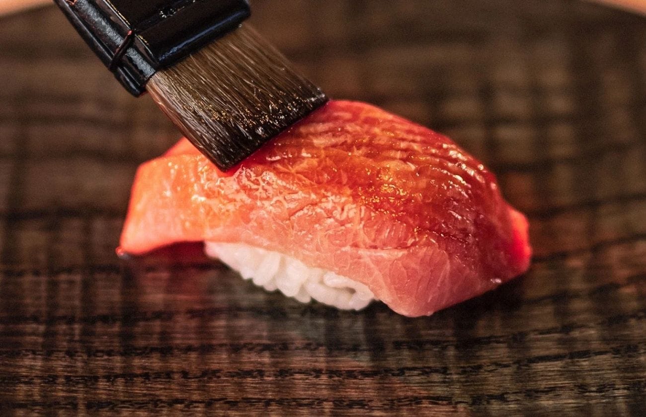 Close-up of fatty tuna nigiri at Yūgin being brushed with house-fermented vinegar for service.